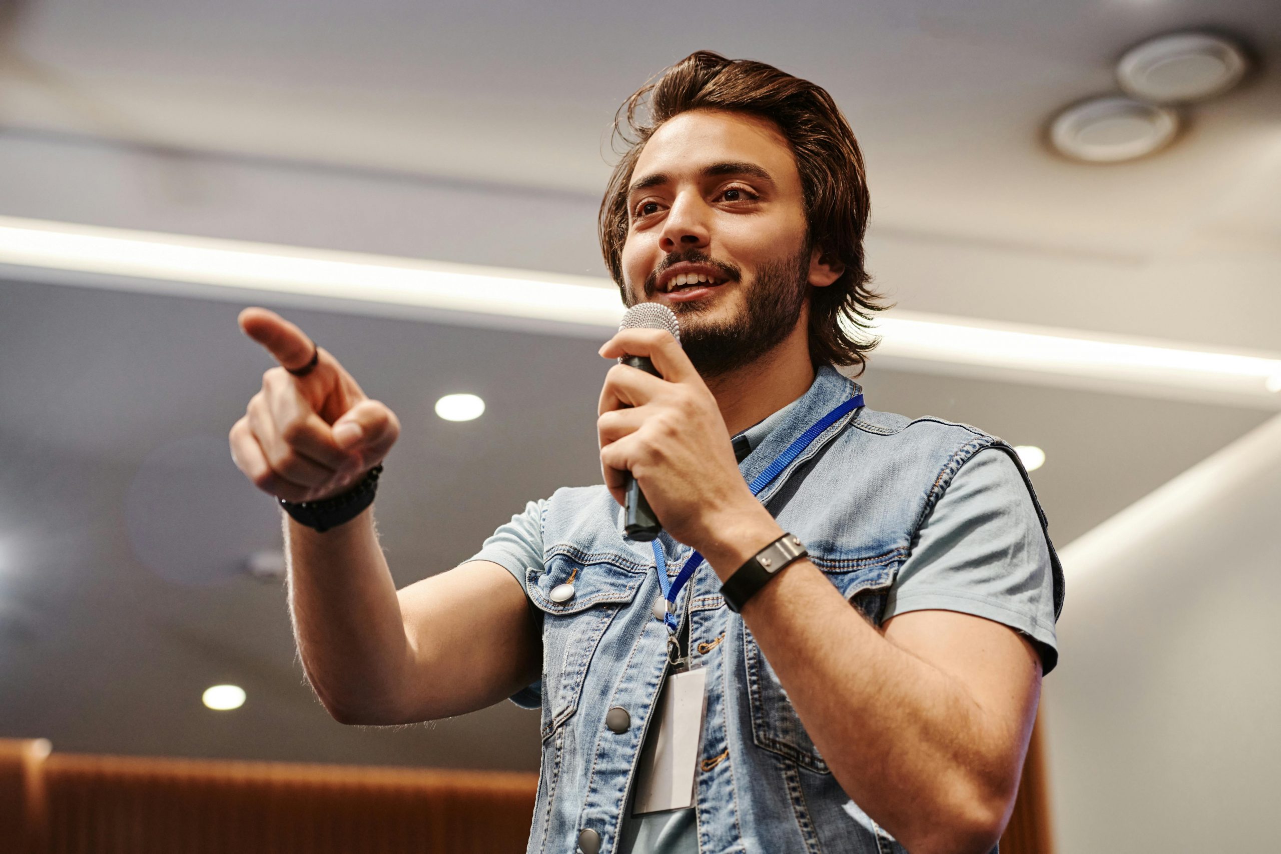 man holding a microphone, speaking to an audience in an event
