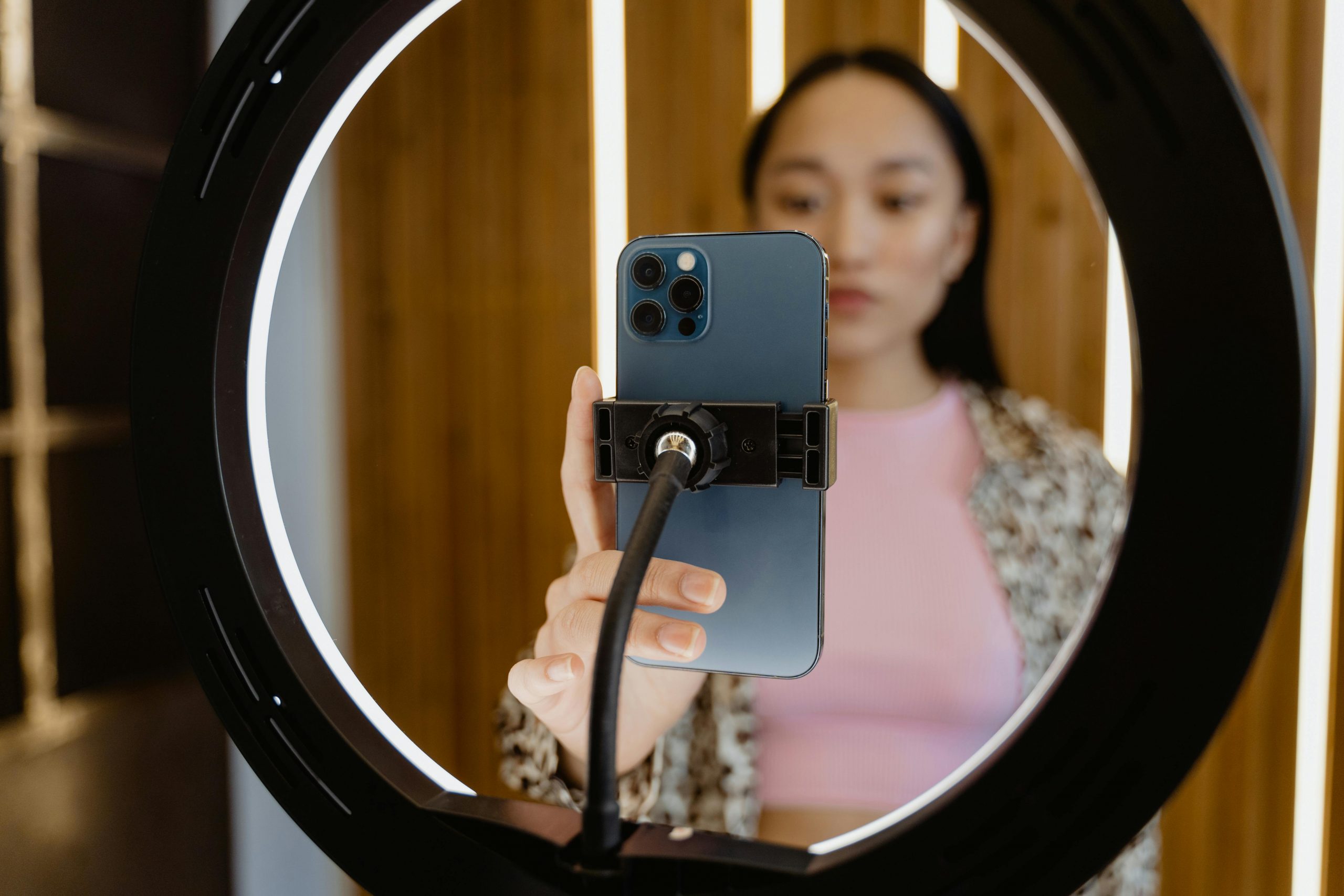 female influencer adjusting her phone mounted on a ring light tripod before recording